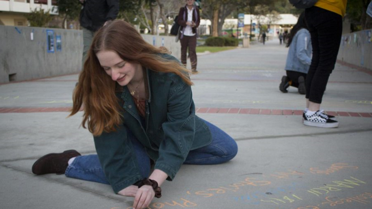 A student writes on the walkway with chalk.